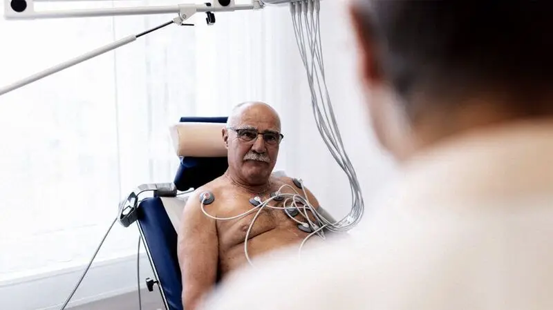 An older man receives an EKG in a doctor's office