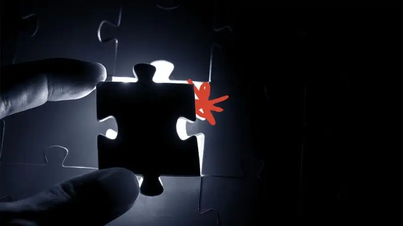 A person putting a piece of puzzle into the correct spot
