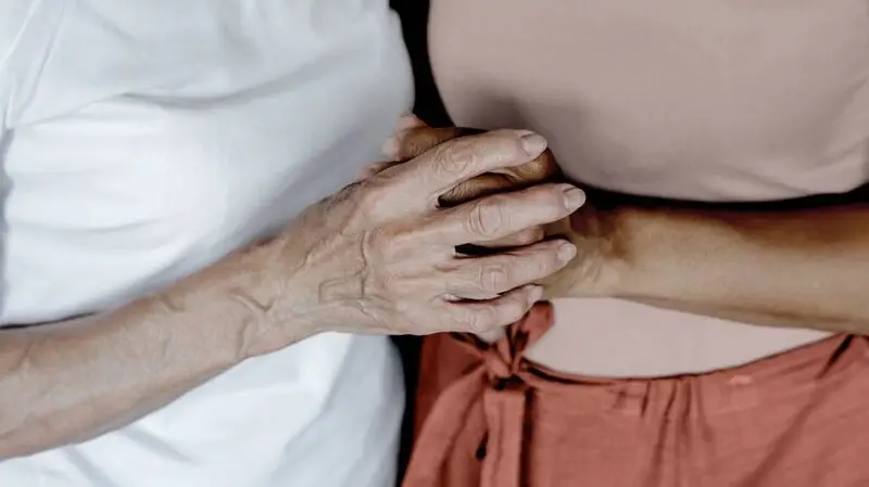 A mother and daughter clasp hands