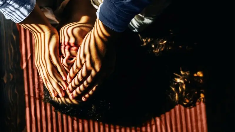 A woman places her hands over her eyes as she lays in the sun