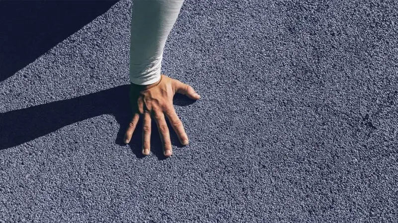 A hand is placed on a textured floor