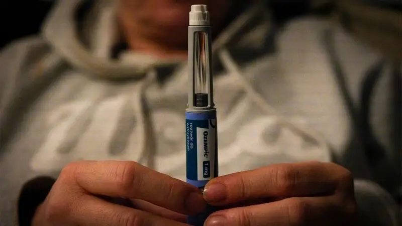 A man holds an injection device used for Ozempic