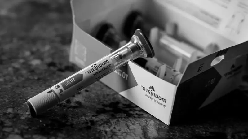 A Mounjaro syringe tube rests against a box