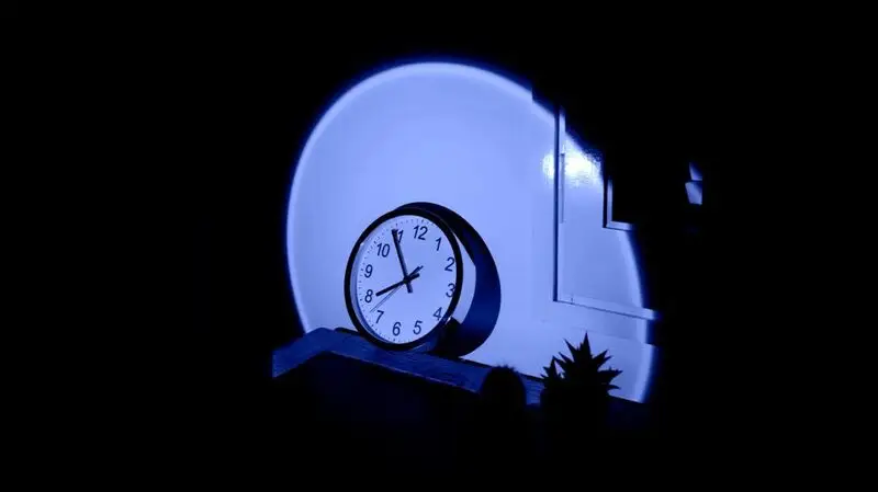 A clock on a nightstand in a dark room