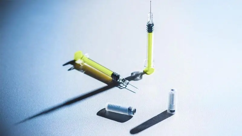 photo of two yellow syringes and two vaccine vials