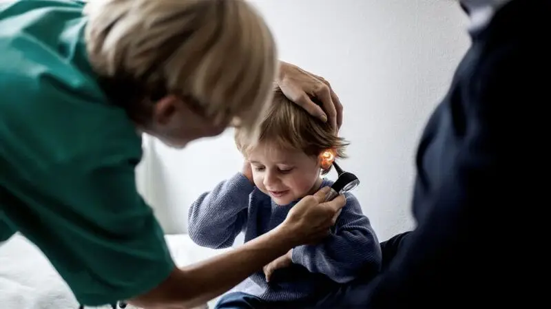 A doctor checks the ear of a young child