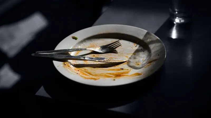 fork and knife resting on dirty empty plate