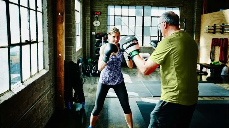 A woman and a man boxing at a gym