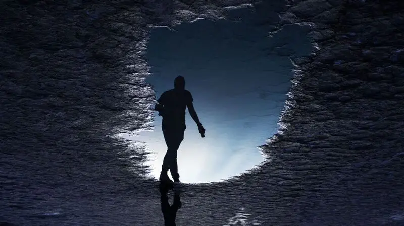 An illustration of a person's silhouette in the dark at a cave entrance