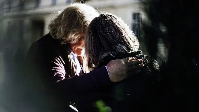 An older woman and older man exchange hugs