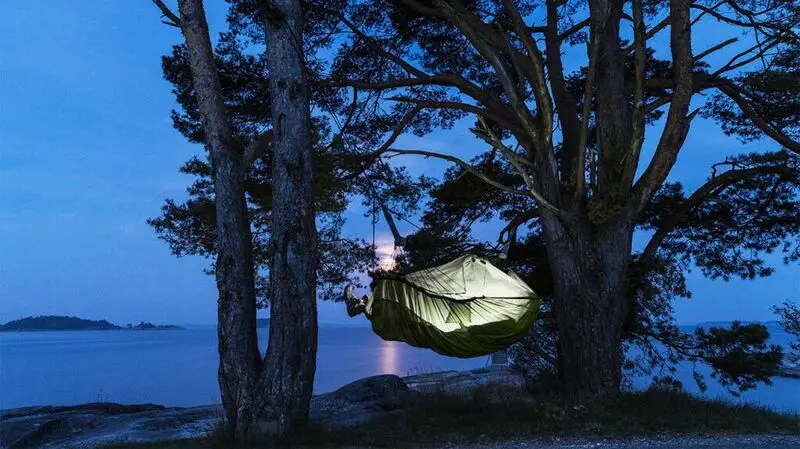 hammock lit for bedtime in blue-tinted natural landscape
