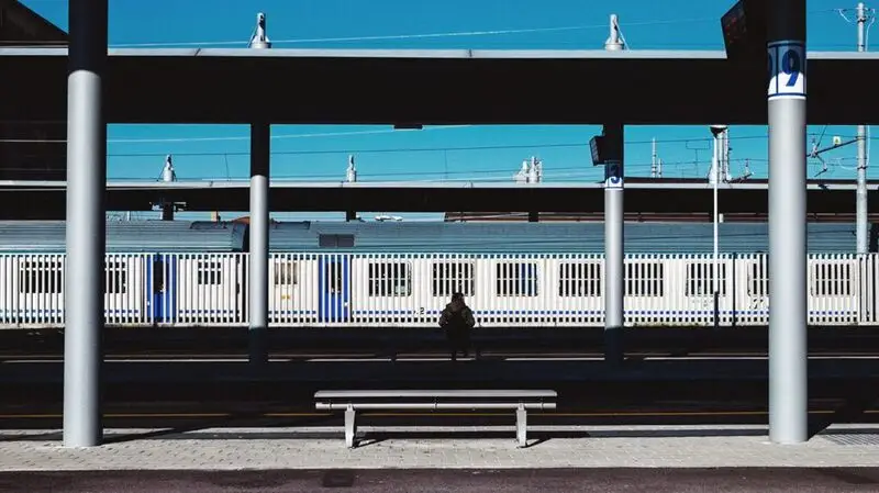 A man sits outside at a train station