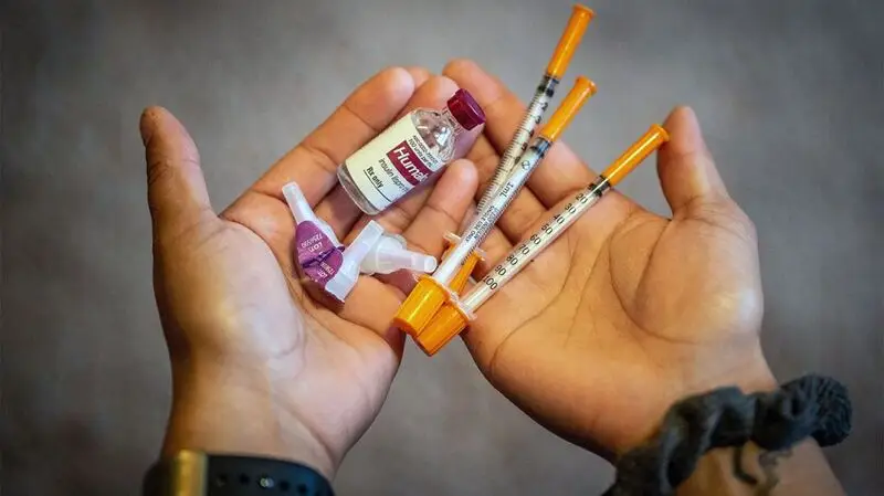 hands holding insulin vials and syringes