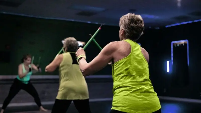 older person wearing neon green tank top exercising at the gym