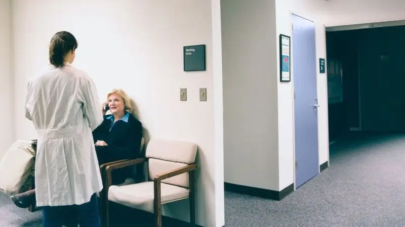 A doctor speaks with a woman in a waiting room