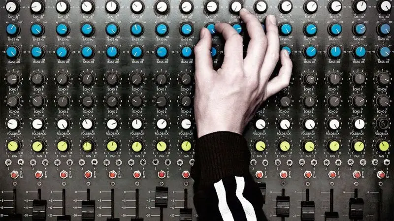 A hand turns up a knob on an audio board