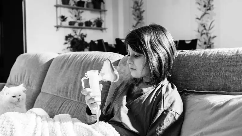 A young girl prepares to use an asthma inhaler