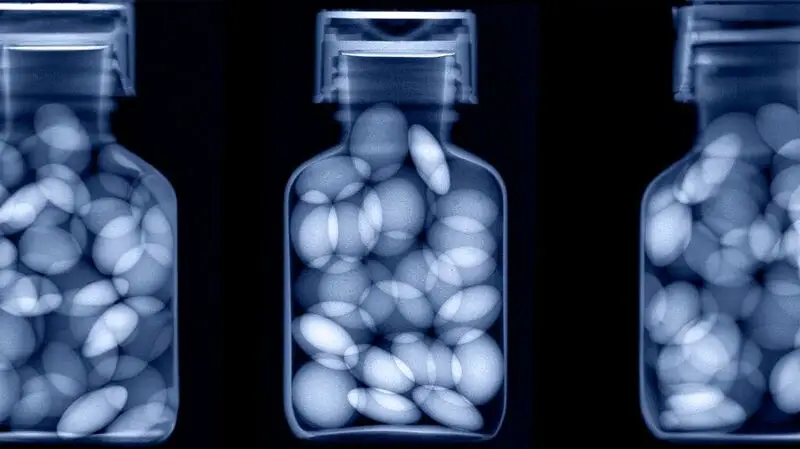 A blue-tinted x-ray of pills in a bottle