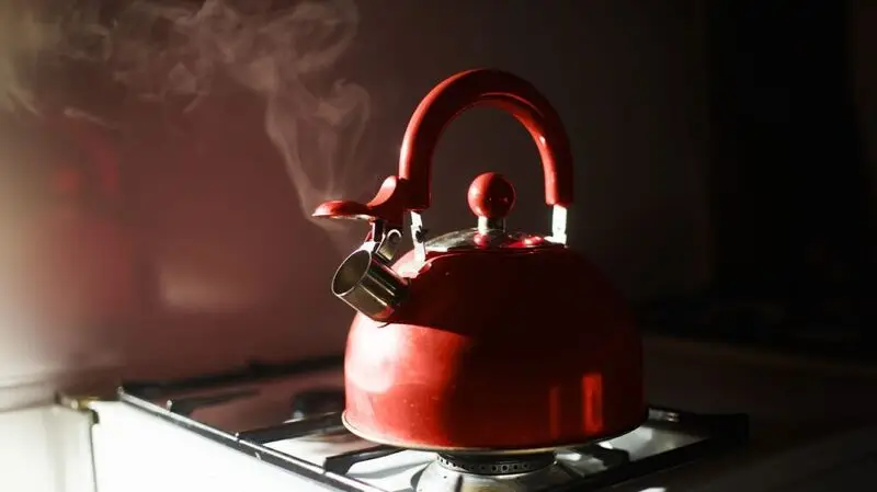 red kettle letting out steam on a stove