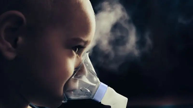 A young girl uses an asthma inhaler