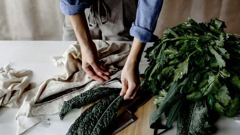 close-up of person's hands as they prepare kale