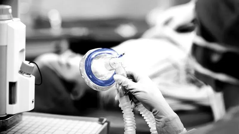 A nurse prepares to put an oxygen mask on a person undergoing surgery