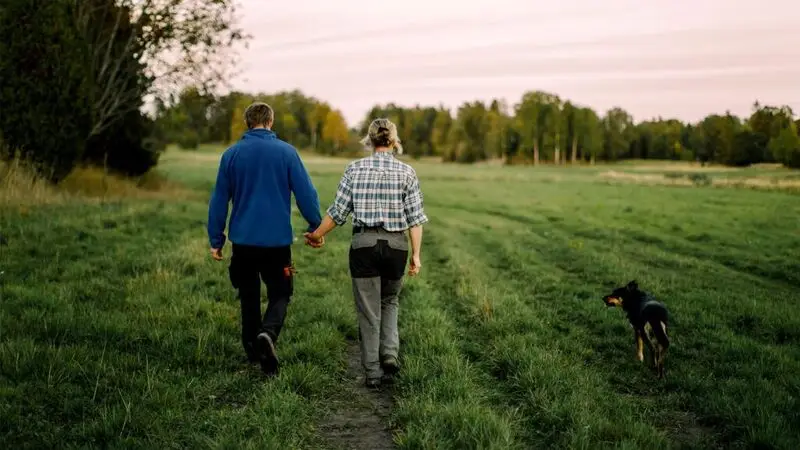 Older couple walking in a field holding hands