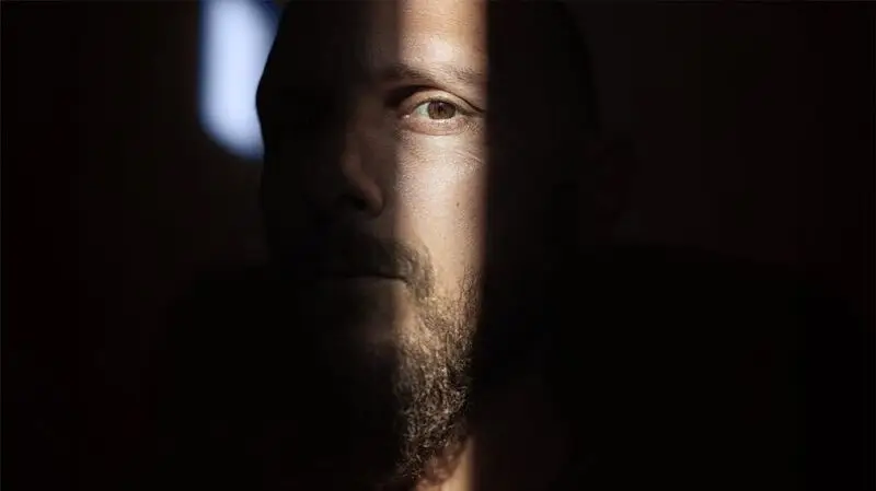 close-up of white, bearded man's face in the shadows