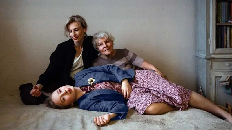 Three multi-generational women in a room leaning on each other