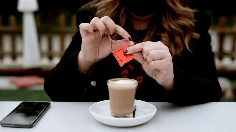 A woman puts artificial sweetener in her coffee