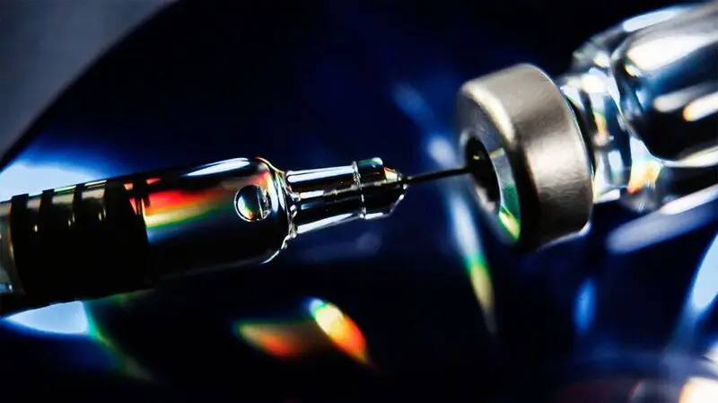 A close up of an injector extracting a dose out of a vial