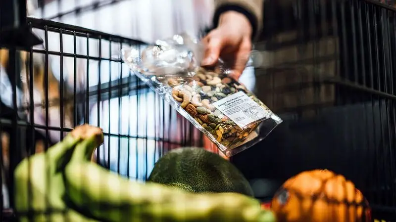 person's hand holding a bag of nuts