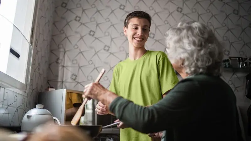 Grandson cooking with grandmother in kitchen