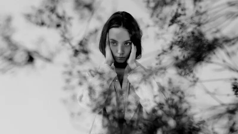 black and white photo of young woman holding her tenmples