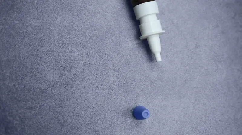 tip of a nasal spray bottle against a gray background