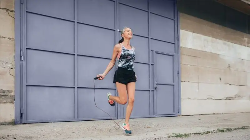 An older woman wearing athletic wear skipping ropes during a workout