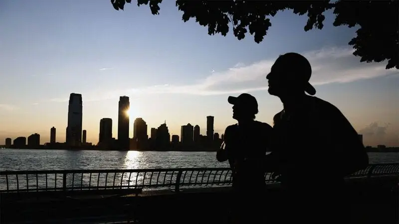 silhouettes of two joggers against New York City skyline