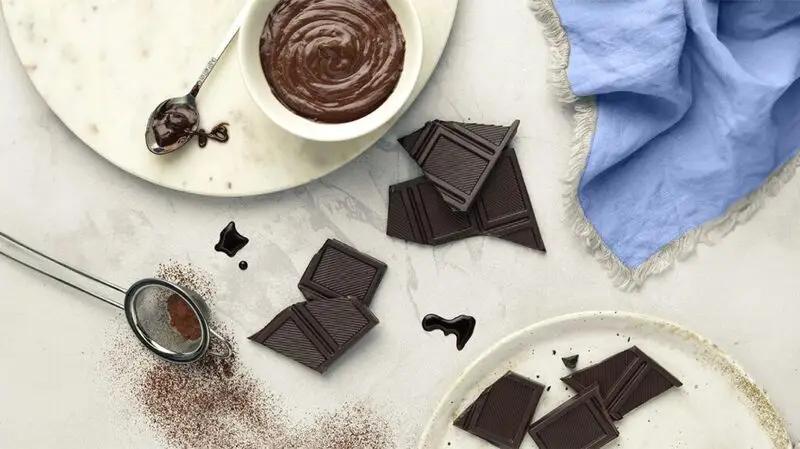 photo of cup containing chocolate cream and bits of dark chocolate on the table