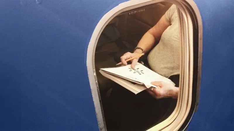 person solving crosswords in in newspaper viewed through plane window