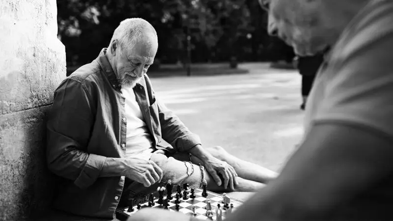 black and white photo of an older man playing chess