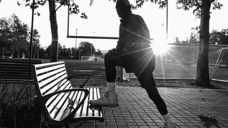 black and white photo of person flexing their knee on a bench