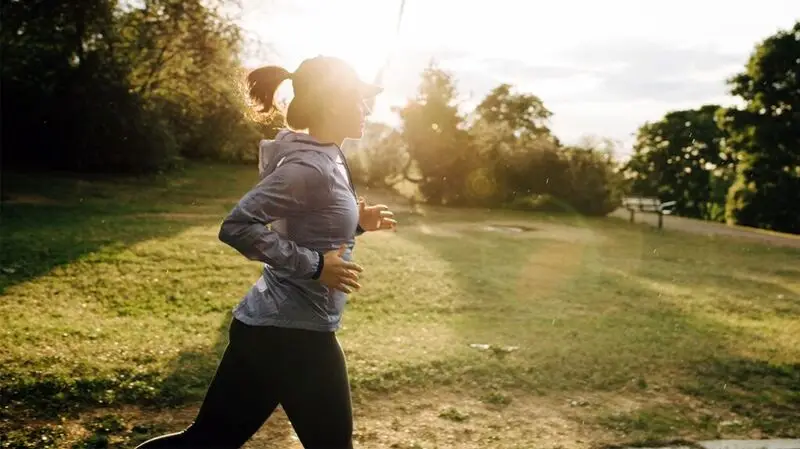 A woman in athletic clothing runs outside at a park