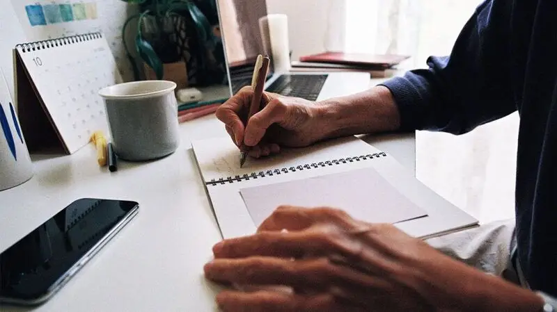 hands holding pen writing in notebook