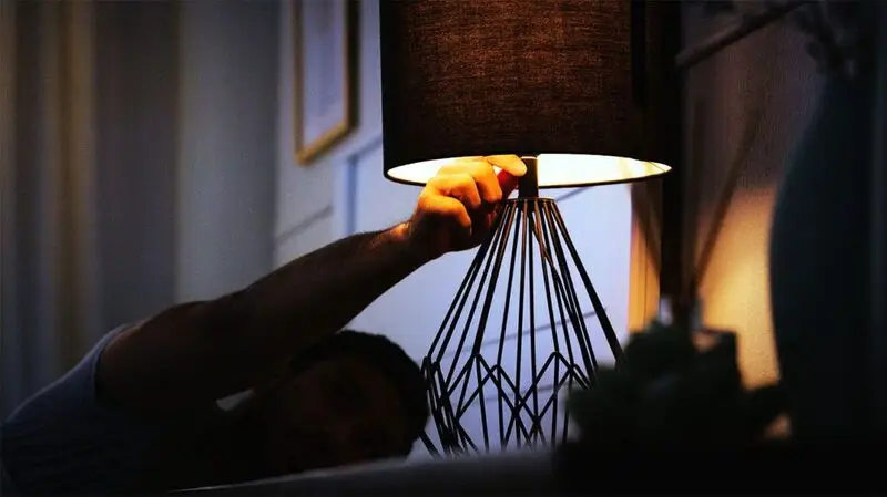 A person getting ready to turn off a night light in a dark room