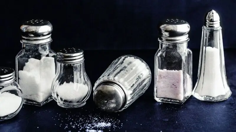 Six salt shakers on a flat surface, two of them toppled over