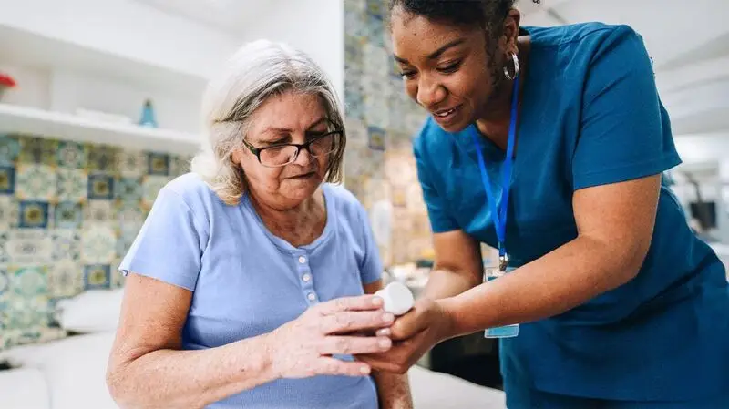 A healthcare professional showing a patient a bottle of medication to instruct them on how to use it properly