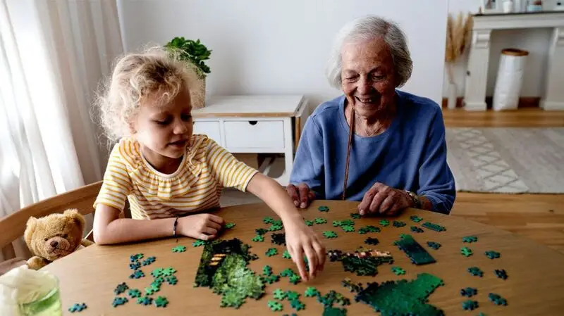 A child doing a puzzle with her grandmother at a table