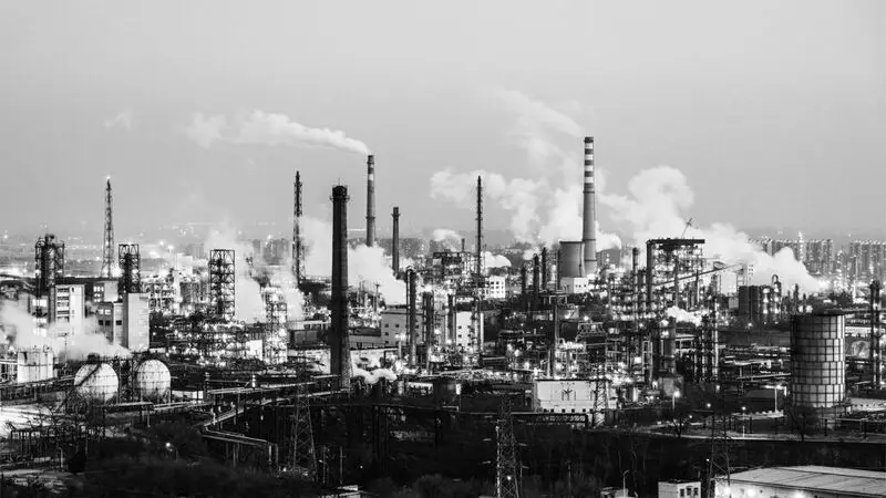 An industrial skyline with smoke billowing from factories