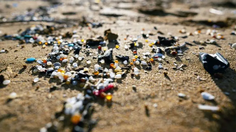 Pieces of plastics on a sandy surface.