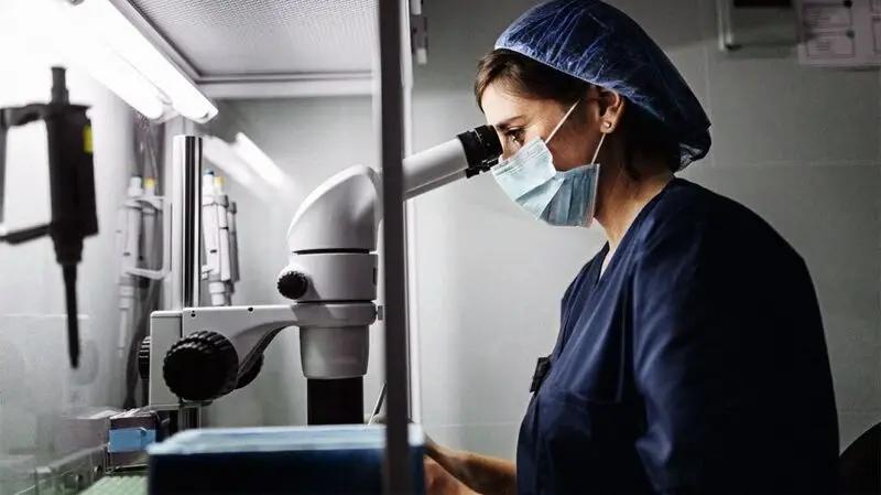 A scientist looks into a microscope to examine cancer cells